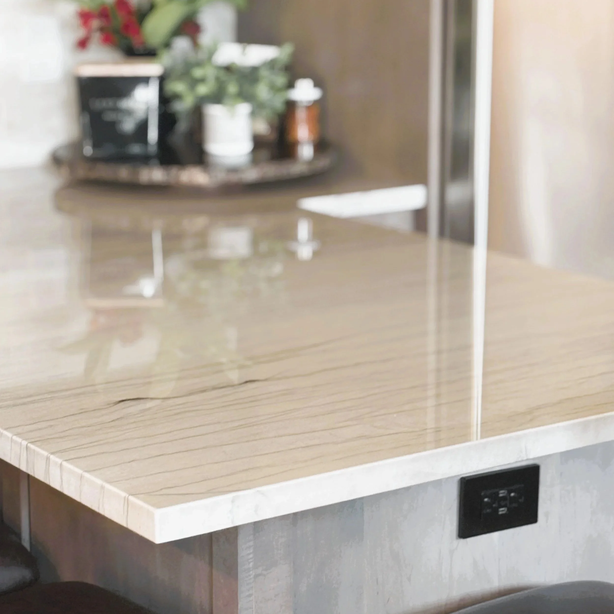 A kitchen countertop with a marble surface, a power outlet, and a dishwasher below.