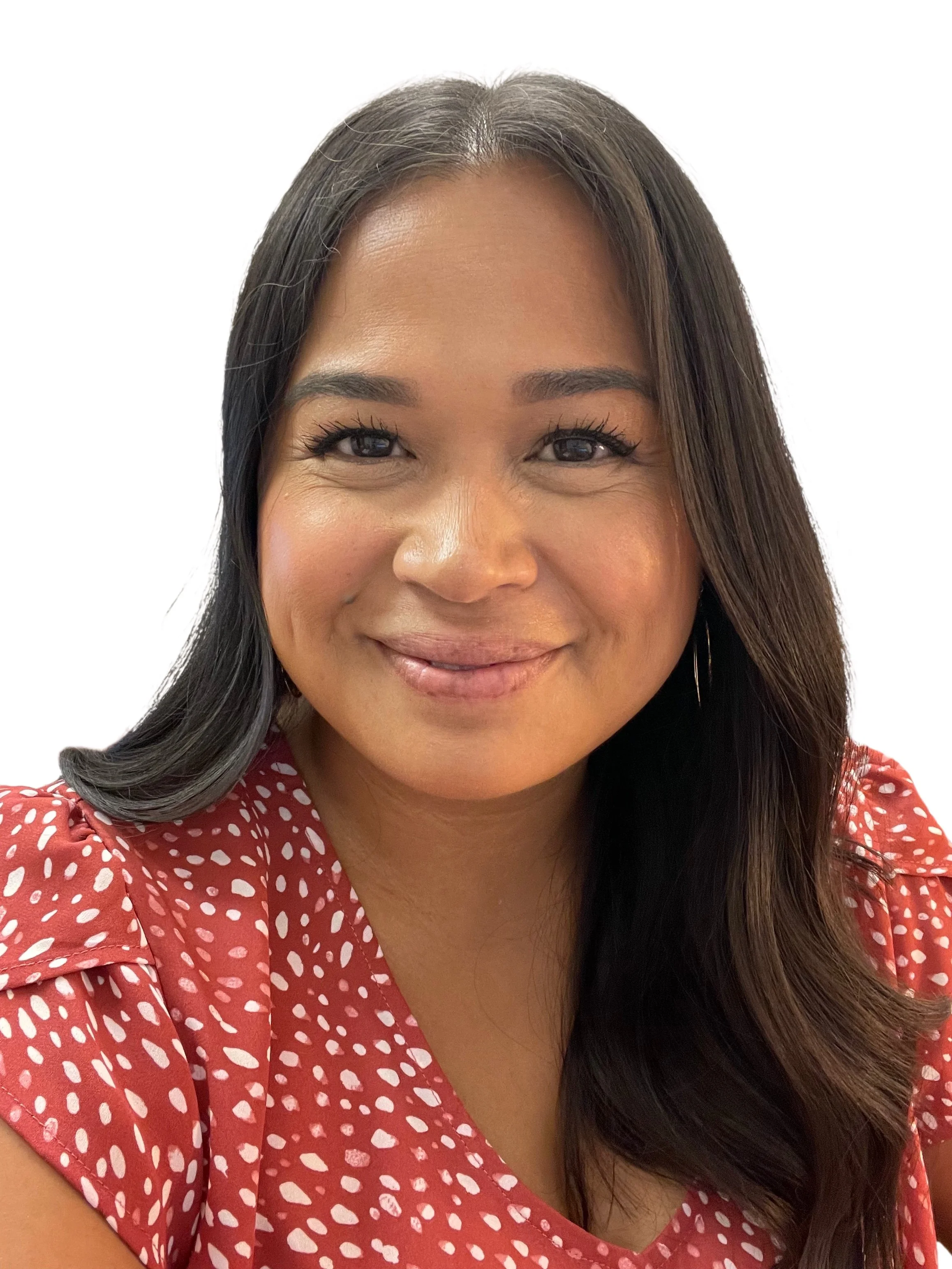 A close-up portrait of a smiling woman with long dark hair, wearing a red blouse with white polka dots and hoop earrings, against a plain white background.