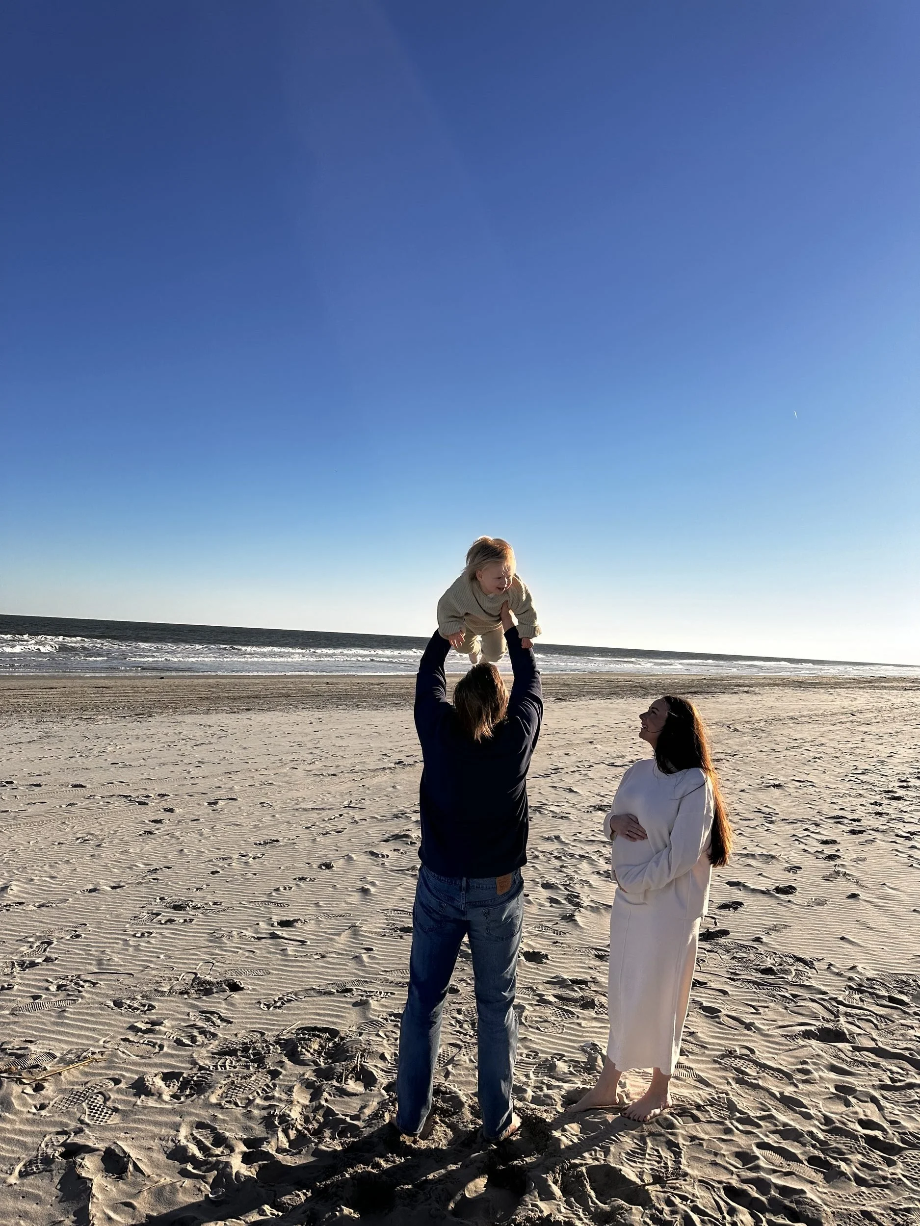 David lifting Luca on the beach while Victoria looks on