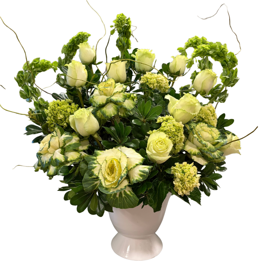 A flower arrangement featuring cream-colored roses, variegated green and white leaves, and other green foliage in a white vase.