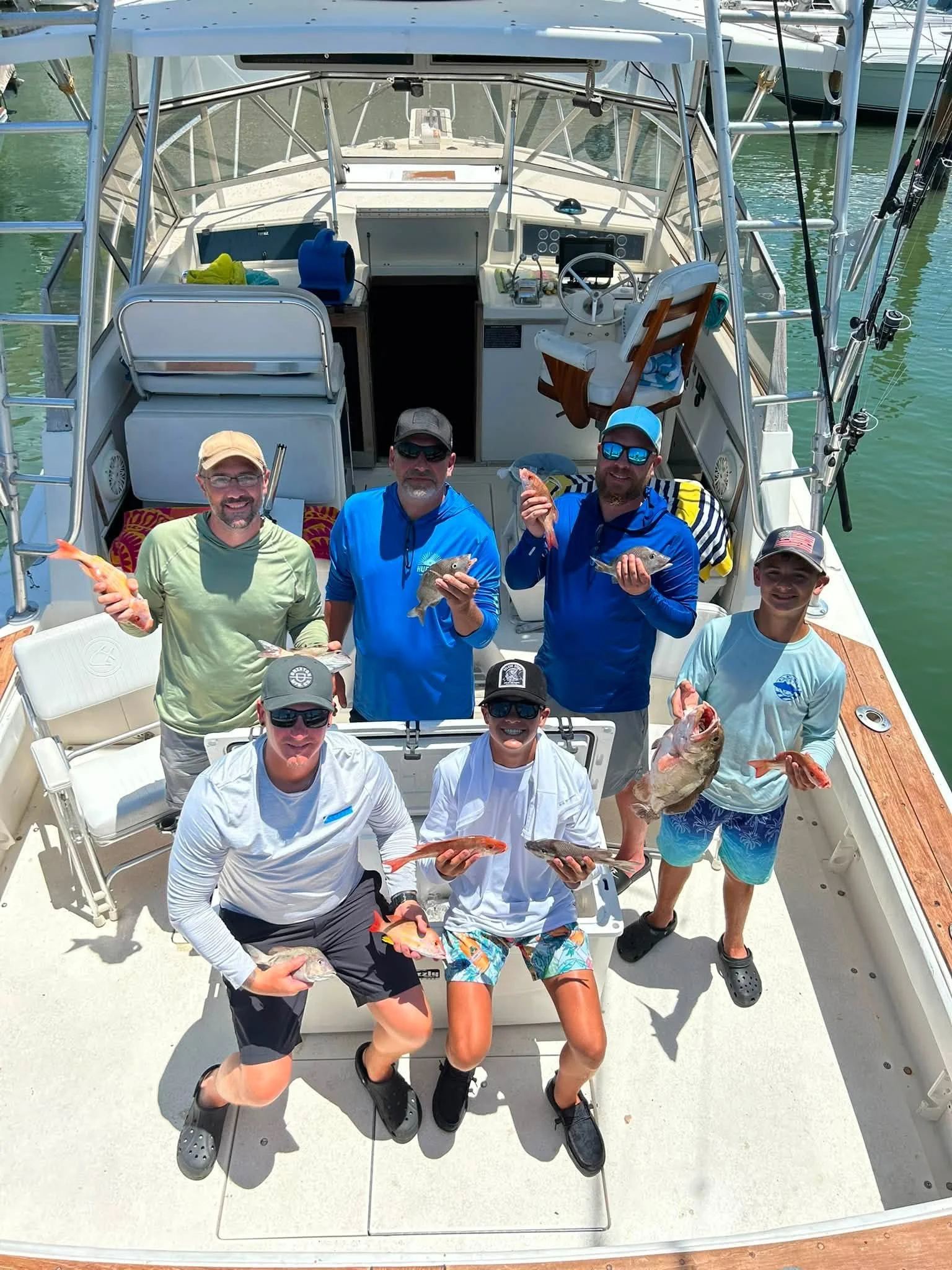 Six anglers displaying their freshly caught fish aboard the Southern Grin fishing charter boat.