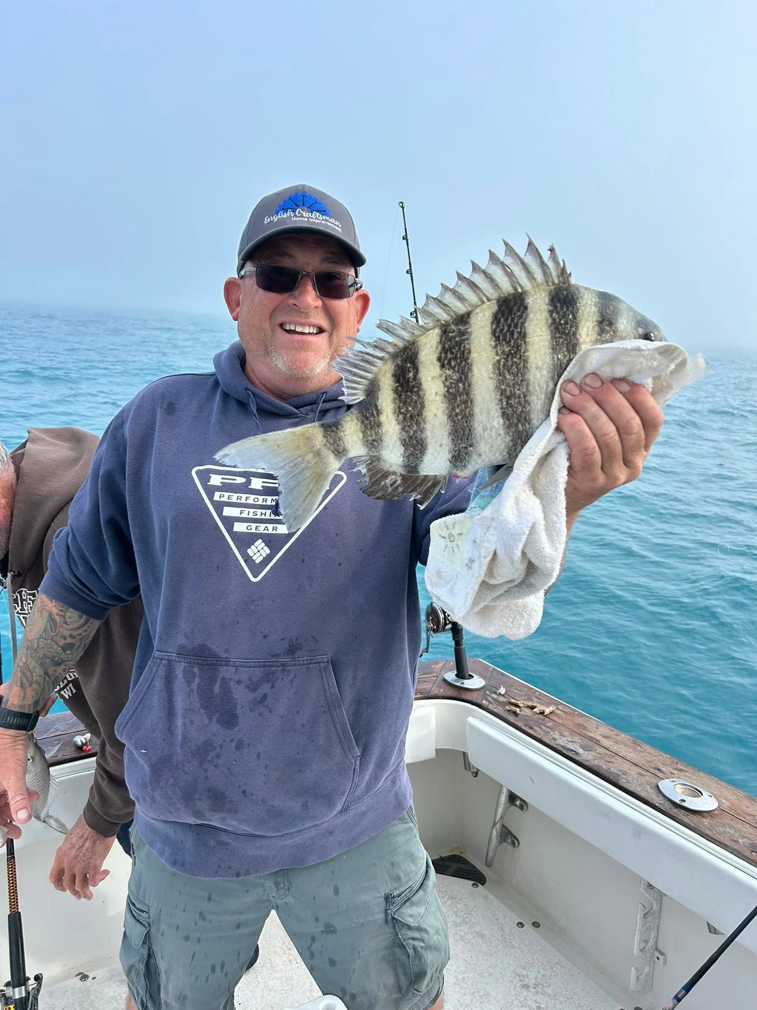 Smiling fisherman holding a large black-and-white striped fish aboard a boat on the Gulf of Mexico.