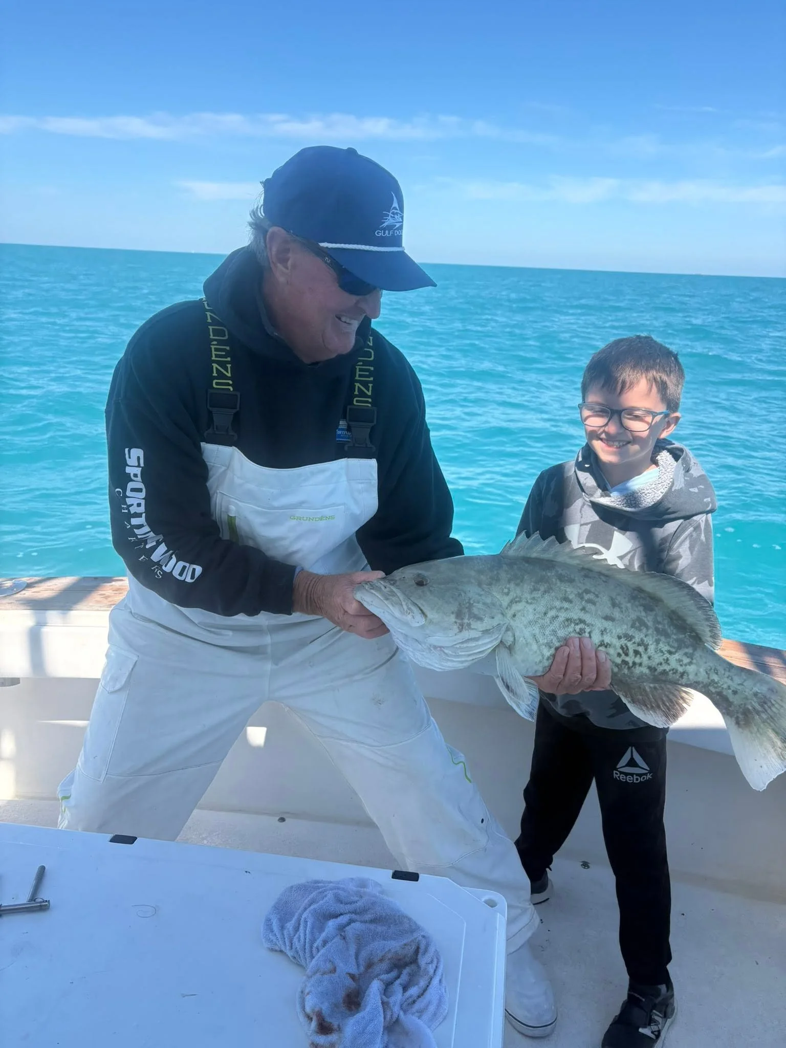 A young angler posing with an adult holding a large fish aboard Southern Grin.