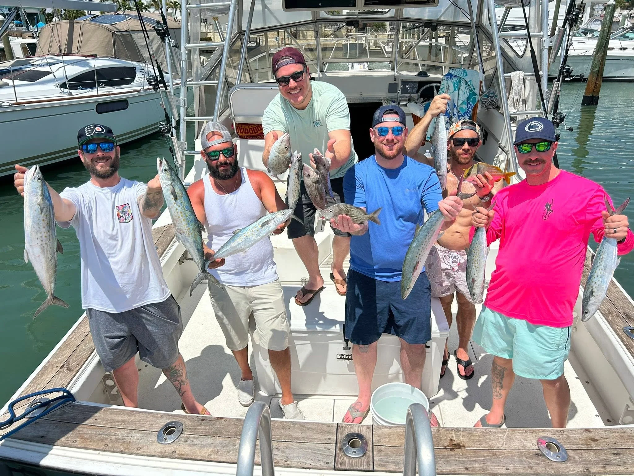 Six smiling anglers displaying their freshly caught fish on the deck of Southern Grin.