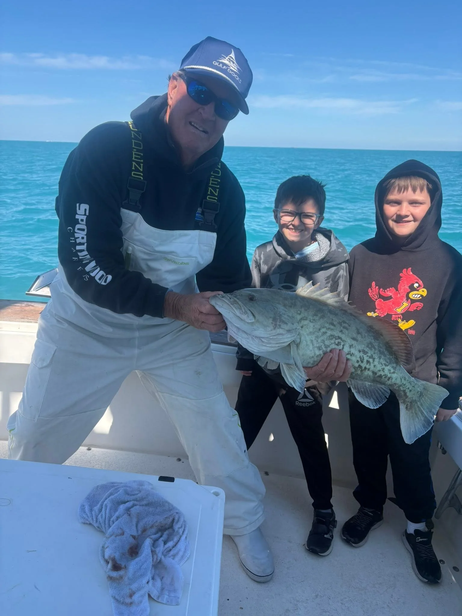 Two young anglers posing with an adult holding a large fish aboard Southern Grin.