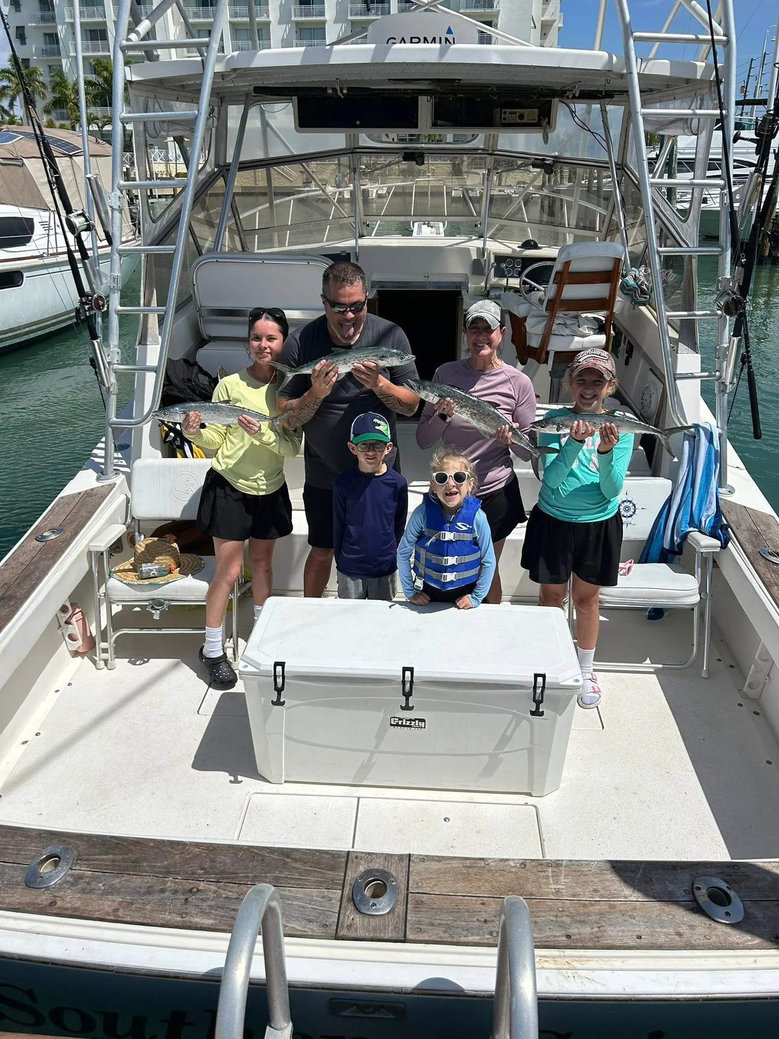 Family group proudly displaying their freshly caught fish on the deck of a charter fishing boat.