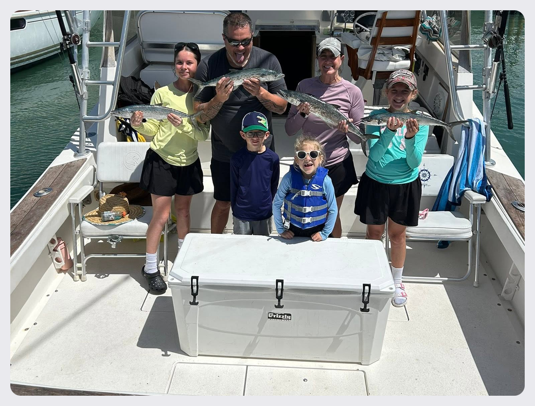 Family posing with their catches aboard the Southern Grin fishing charter boat.