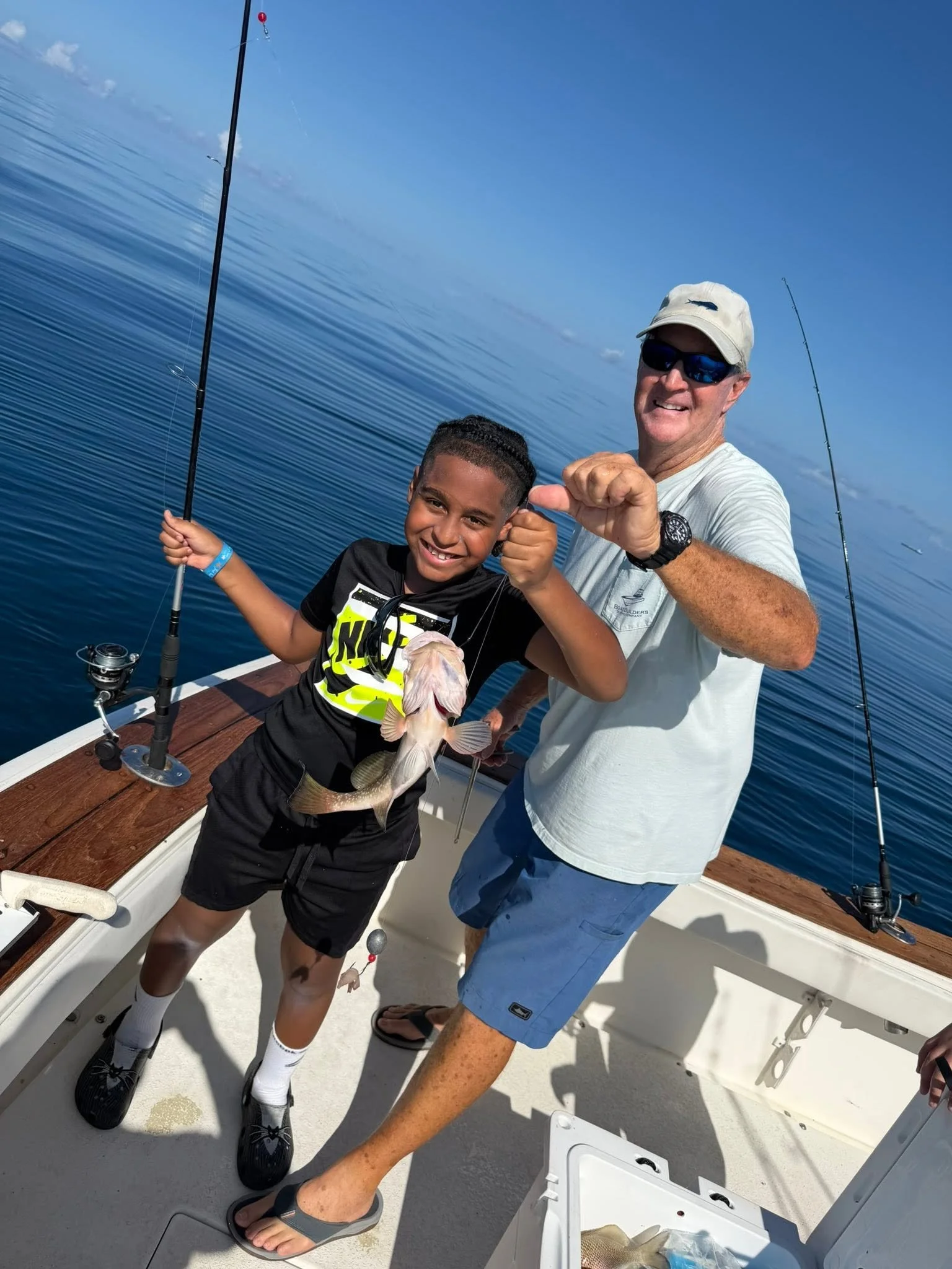 Young angler proudly showing his catch alongside an adult aboard a fishing boat on the Gulf of Mexico.