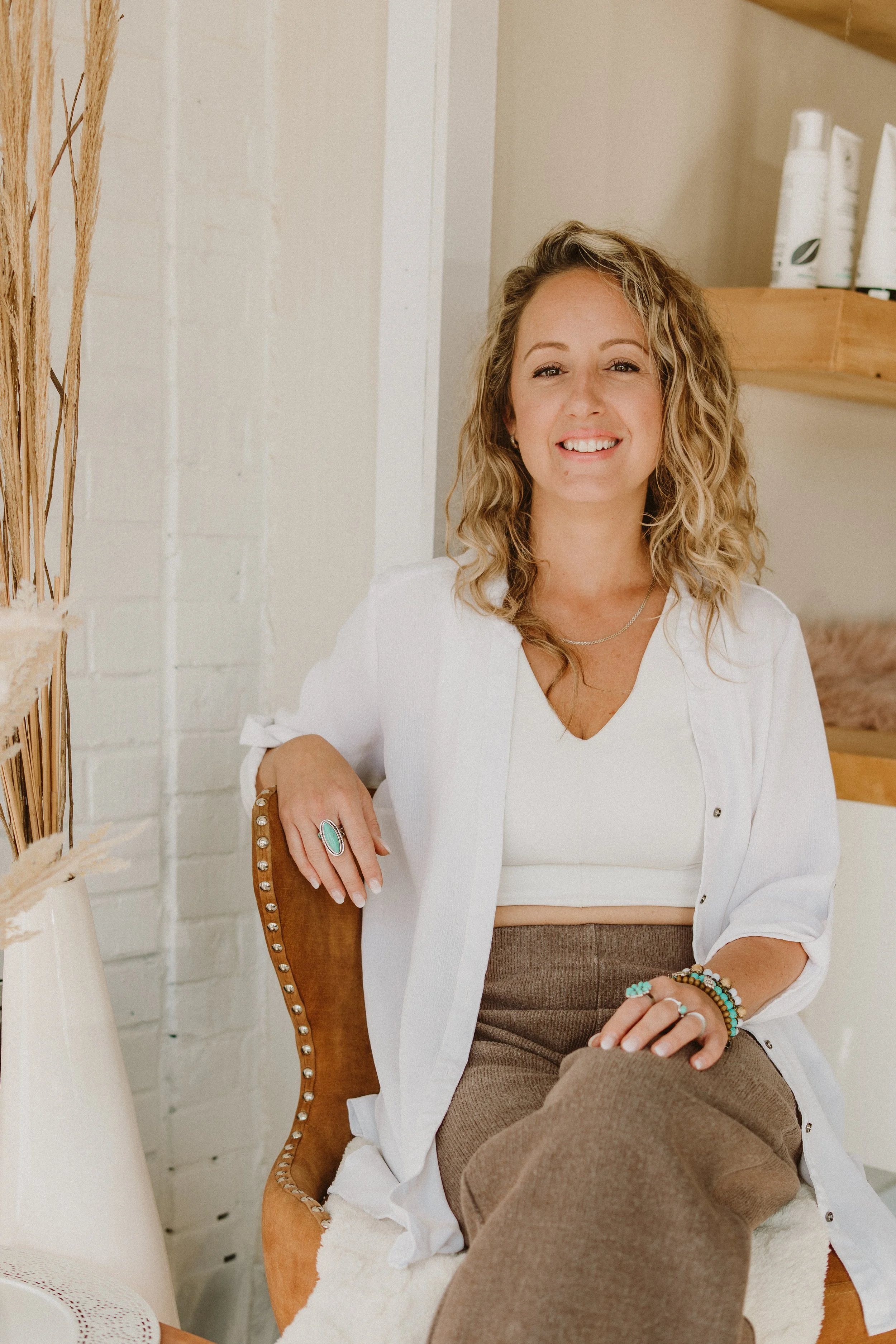 Émilie Giguère dans son salon d'esthétique Espace M. Elle est dans un intérieur lumineux avec un mur blanc et des étagères en bois en arrière-plan.