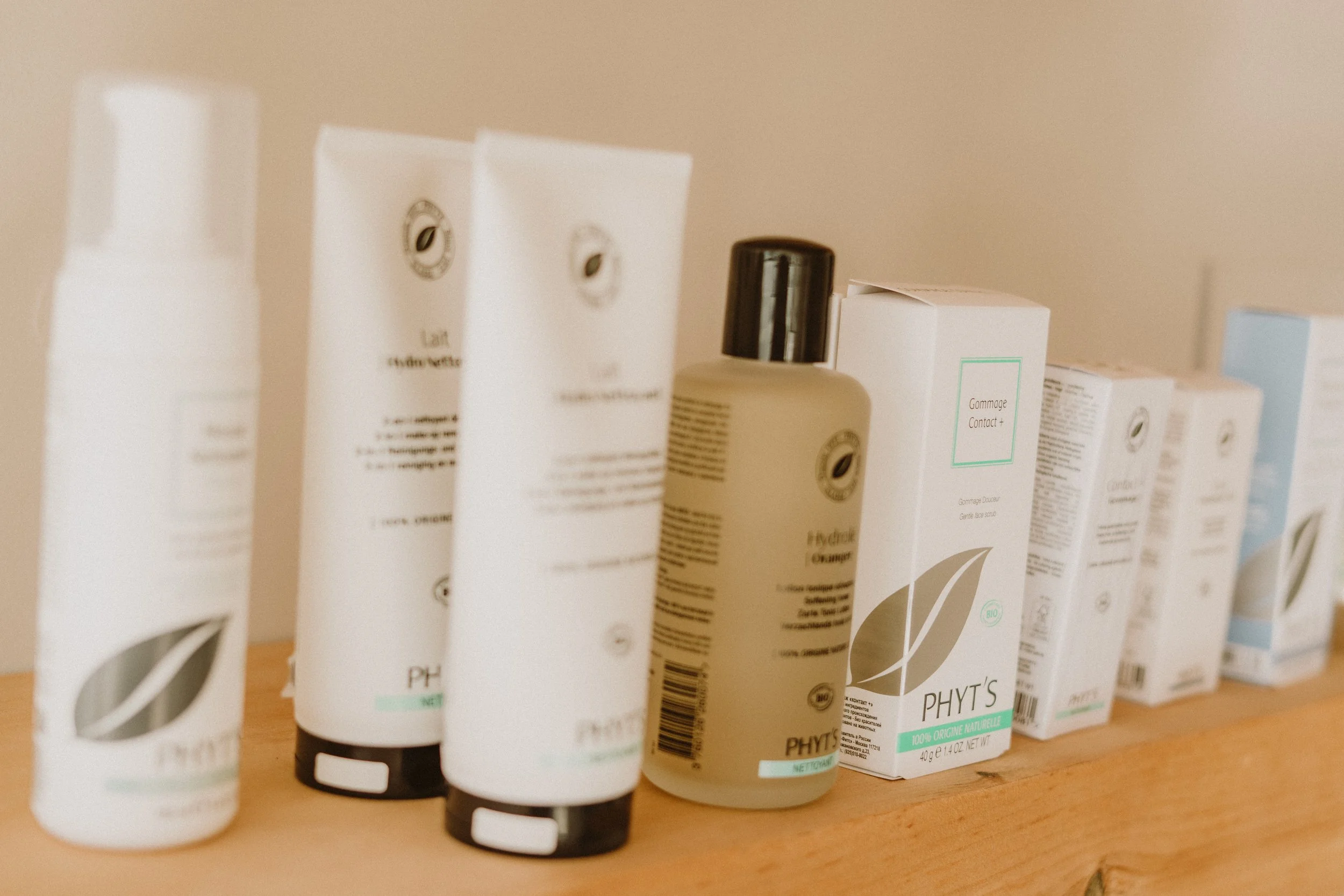 Différents produits de soins pour la peau, produits Phyt's, y compris des tubes et des bouteilles, disposés sur une surface en bois.