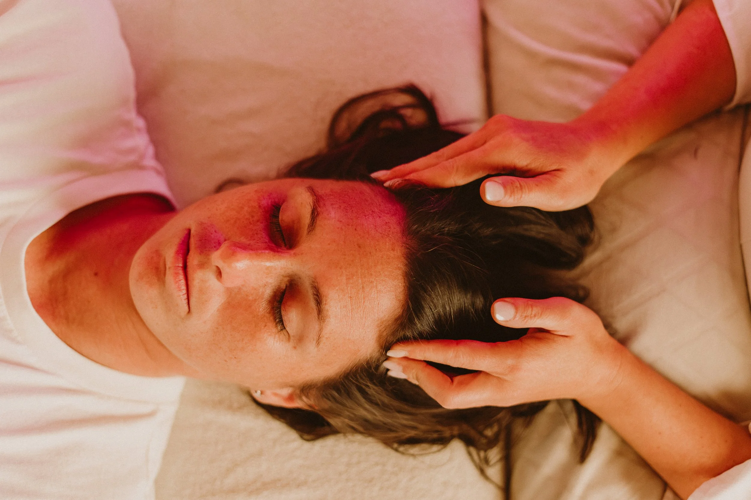 Une femme reçoit un soin énergétique dans une clinique de Lachute, allongée sur le ventre, avec le visage tourné de côté, les yeux fermés, dans un environnement relaxant.