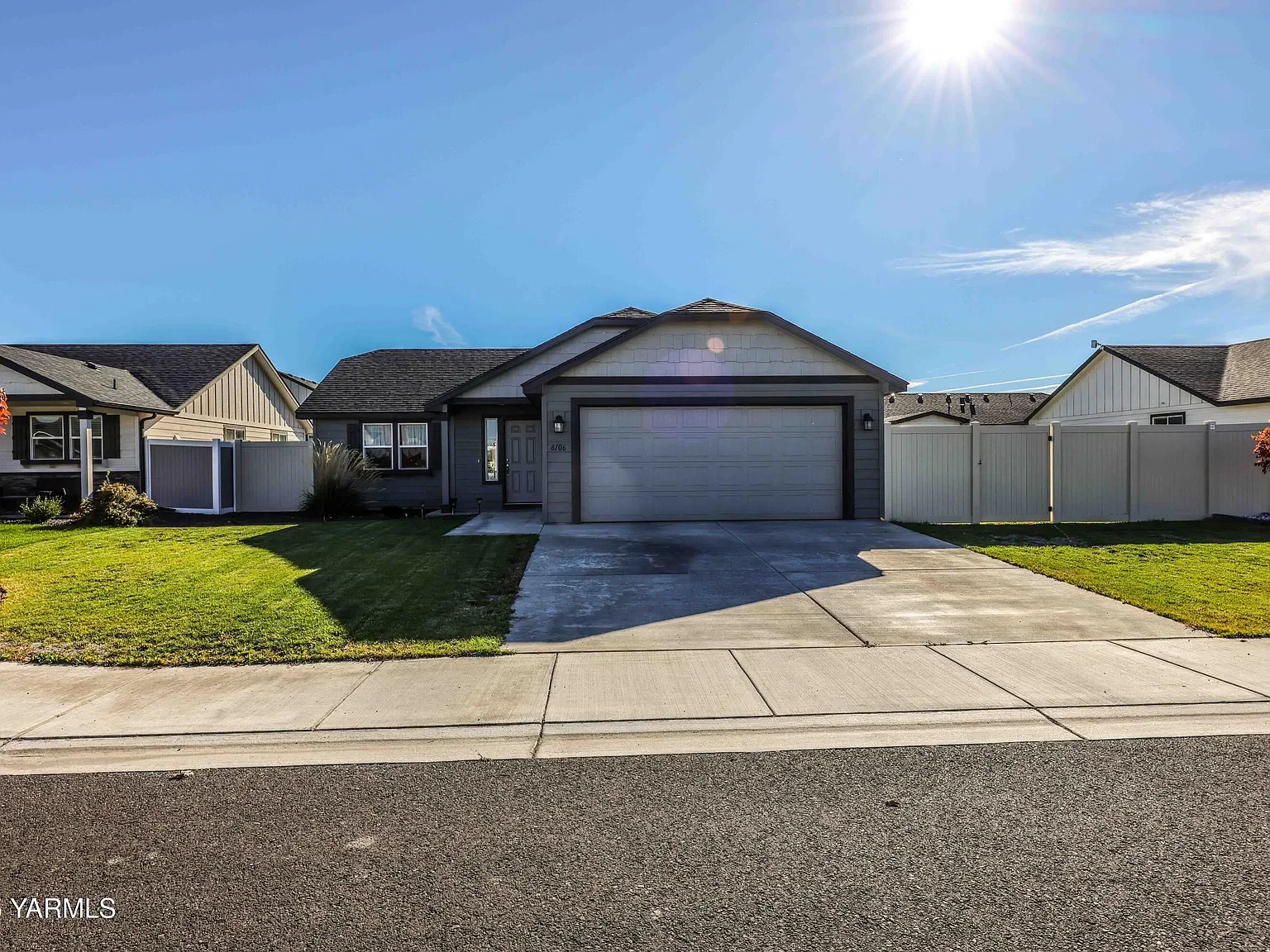 Front view of a house with a two-car garage, driveway, and front yard on a sunny day.