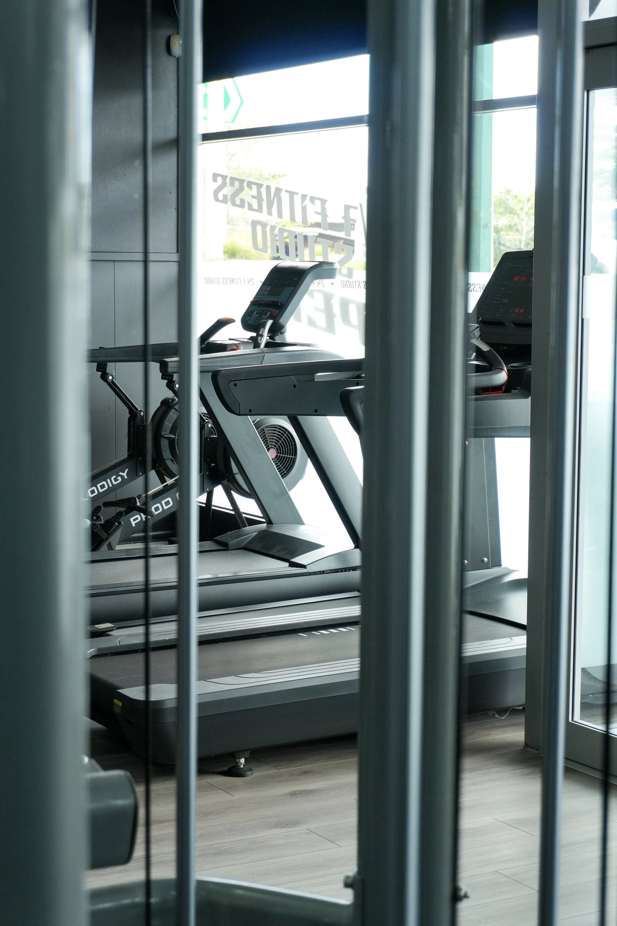 Treadmill inside a gym, viewed through metal bars.