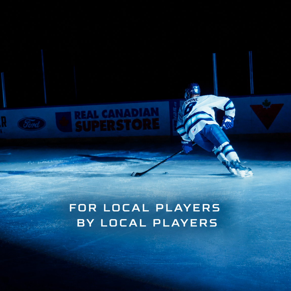 Ice hockey player in a white and blue jersey skating on ice at night, with a sign in the background reading 'Real Canadian Superstore' and the text 'For local players by local players' overlaid.