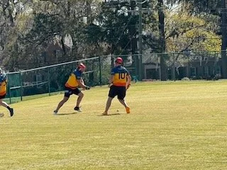 Two young baseball players on a field, one catching a ball and the other running with a bat.