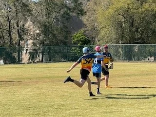 Children playing flag football on a grassy field.