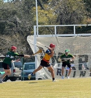 Lacrosse players in red and green uniforms practicing on a field with a goal in the background.