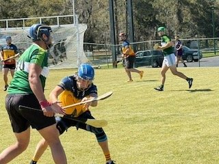 Children playing flag football on a grassy field, wearing helmets and colorful jerseys.
