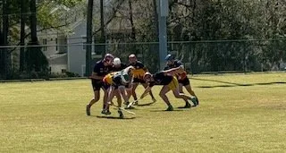 Youth football players on a field during a game, engaging in a play.