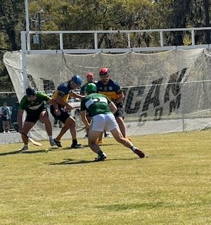A group of young football players on a field during practice or a game, with some players wearing helmets and jerseys in different colors, and a large netted goal in the background.