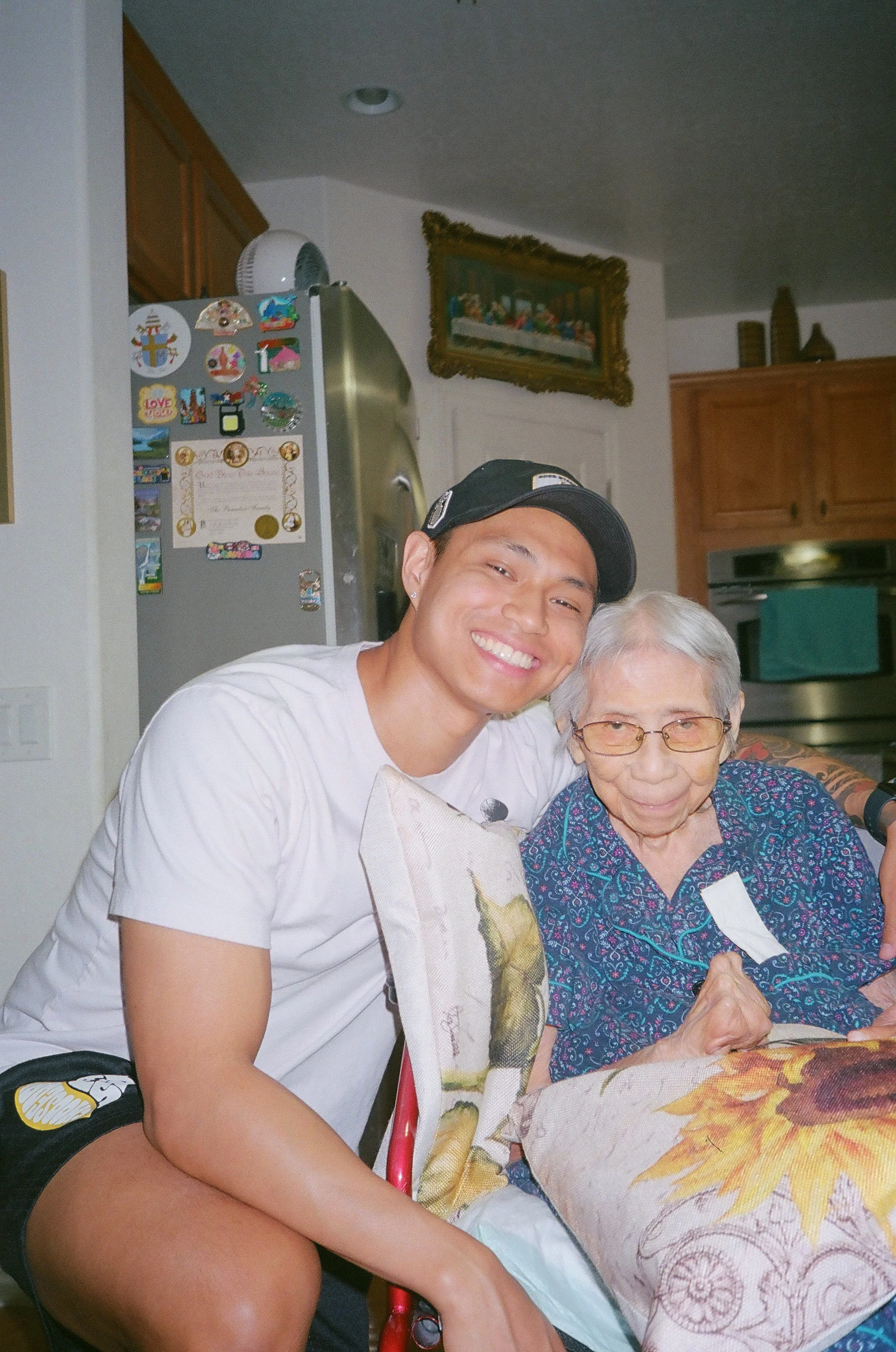 Chris Punsalan smiling beside his grandmother while spending time together at home.
