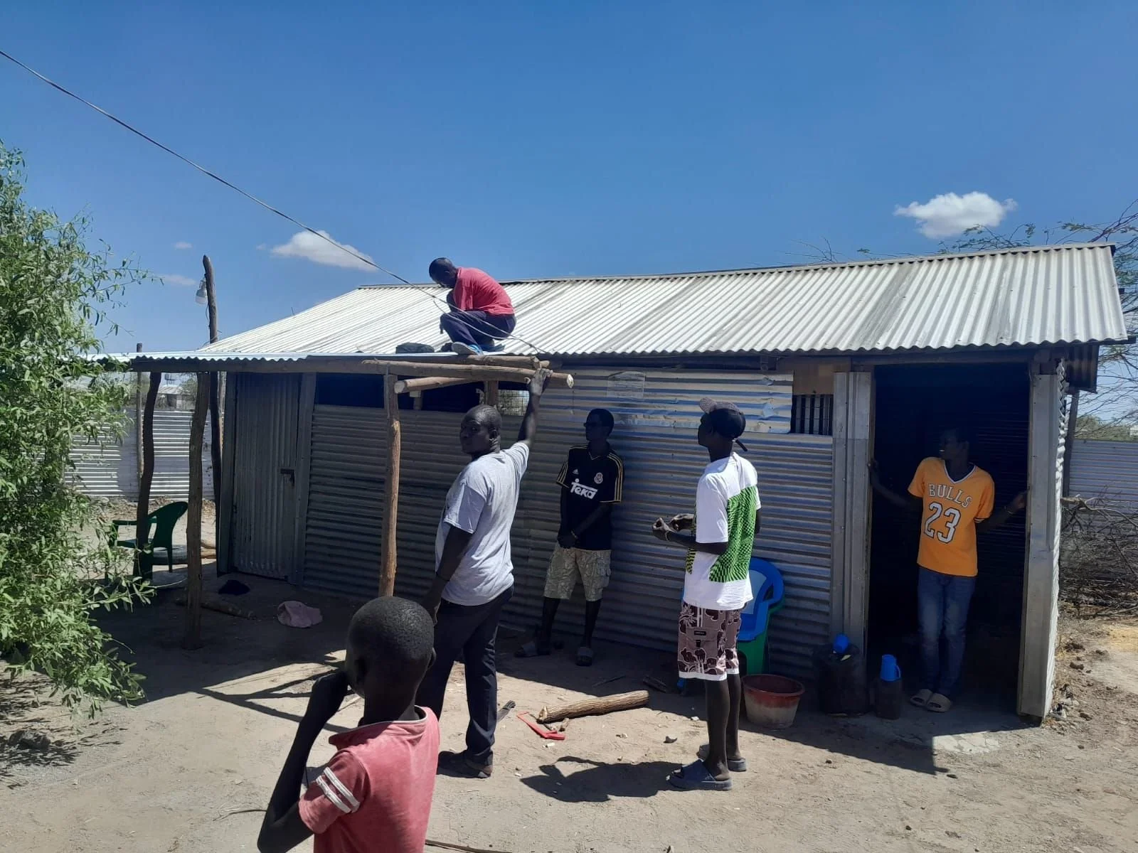 A team adds shade to the serving area outside the school kitchen in Kalobeyei.