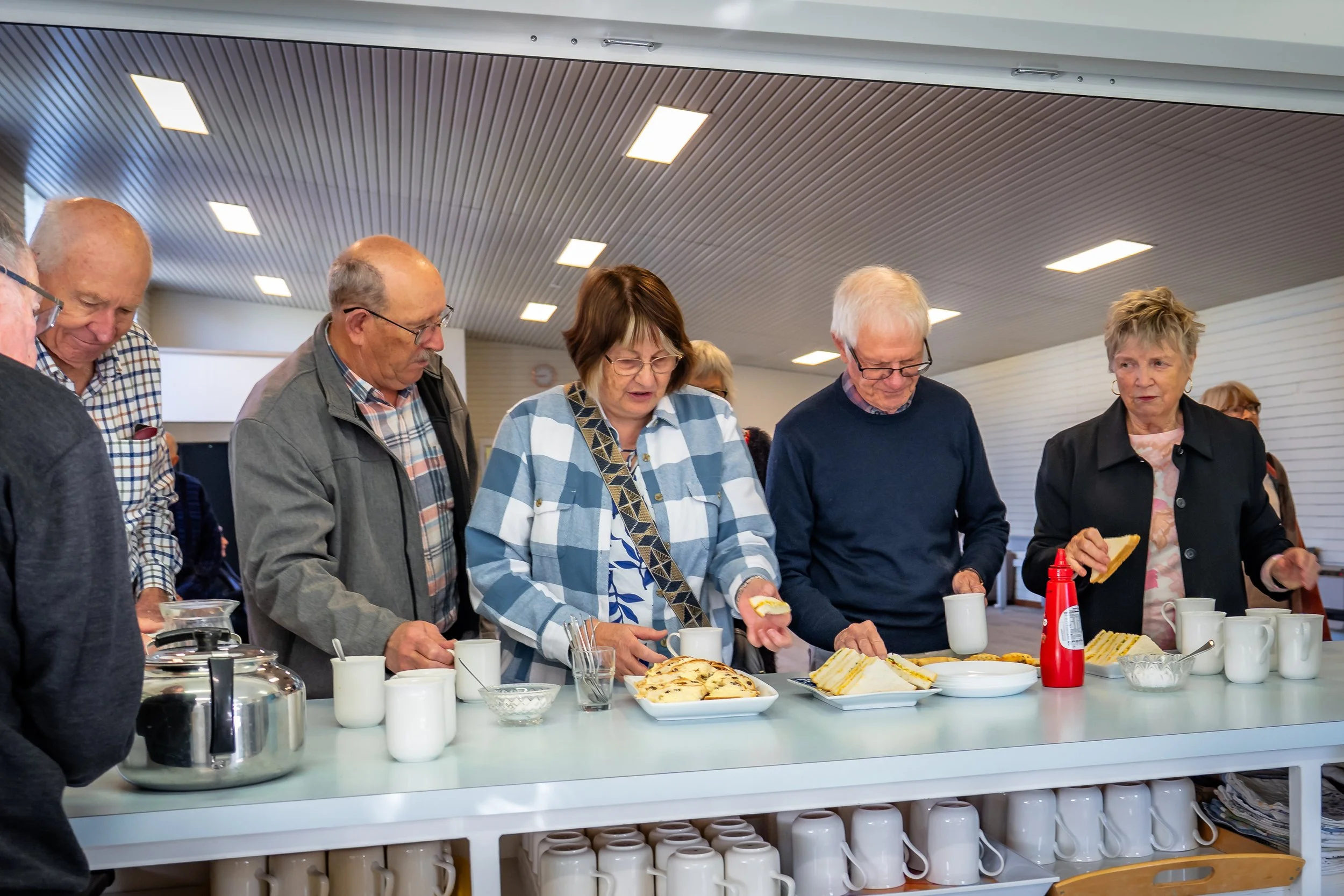 Church members sharing morning tea around the kitchen counter.