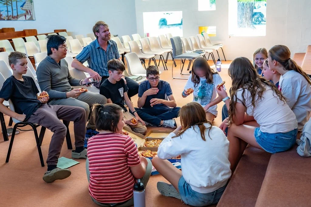 Young people and leaders sharing food and conversation, with existing privacy blurs preserved