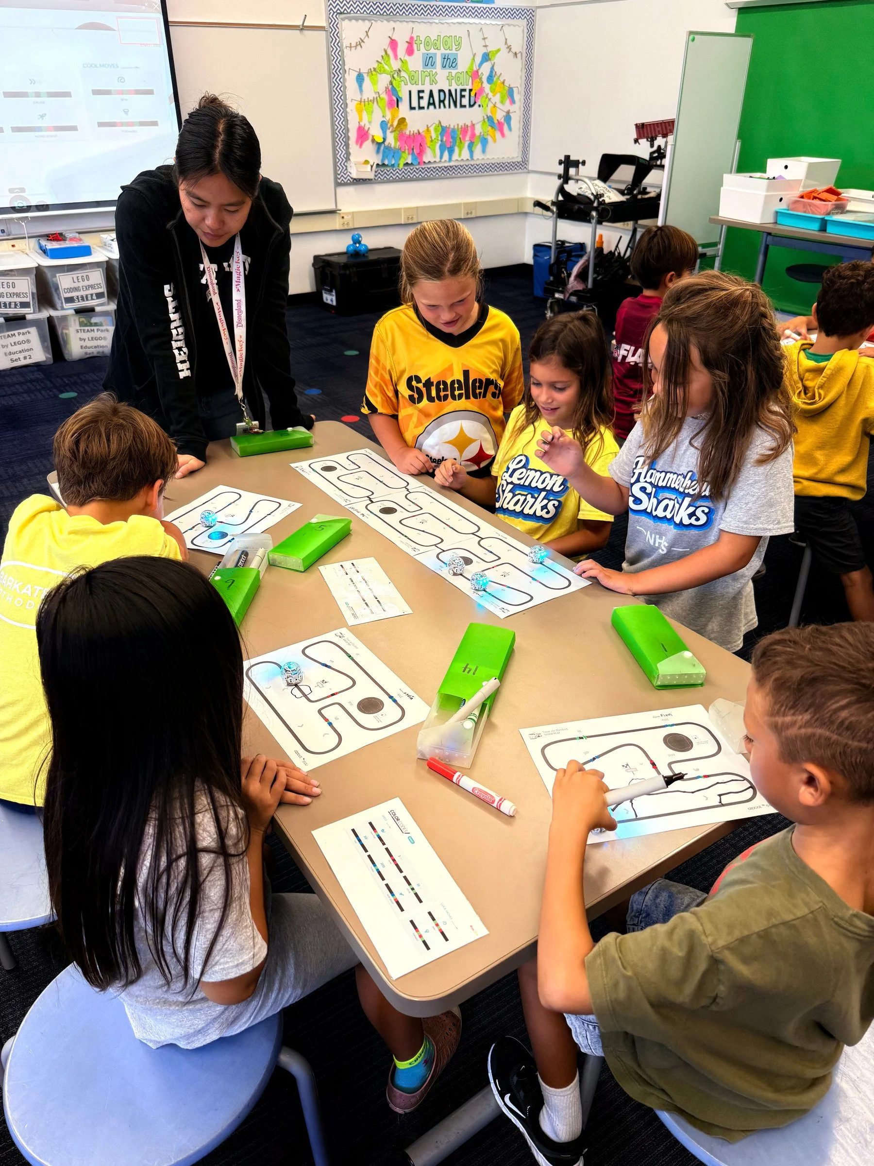 Students explore Ozobot coding paths with their teacher in the Shark Tank.