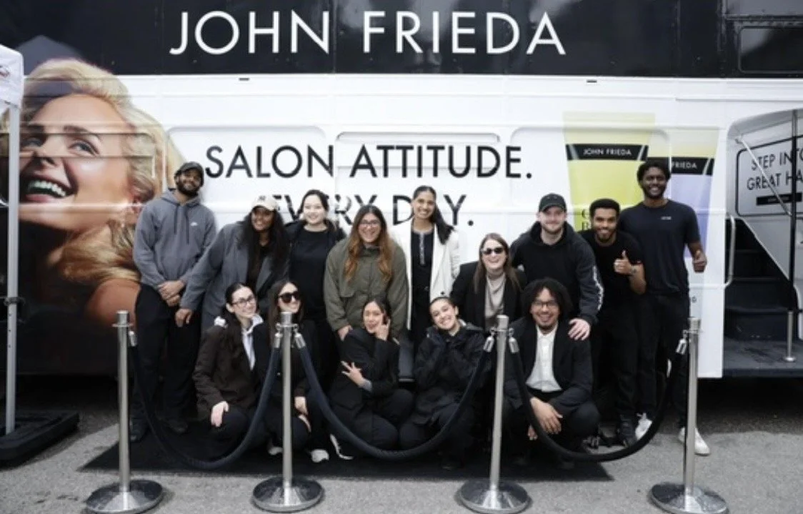 Group posing in front of a John Frieda salon trailer