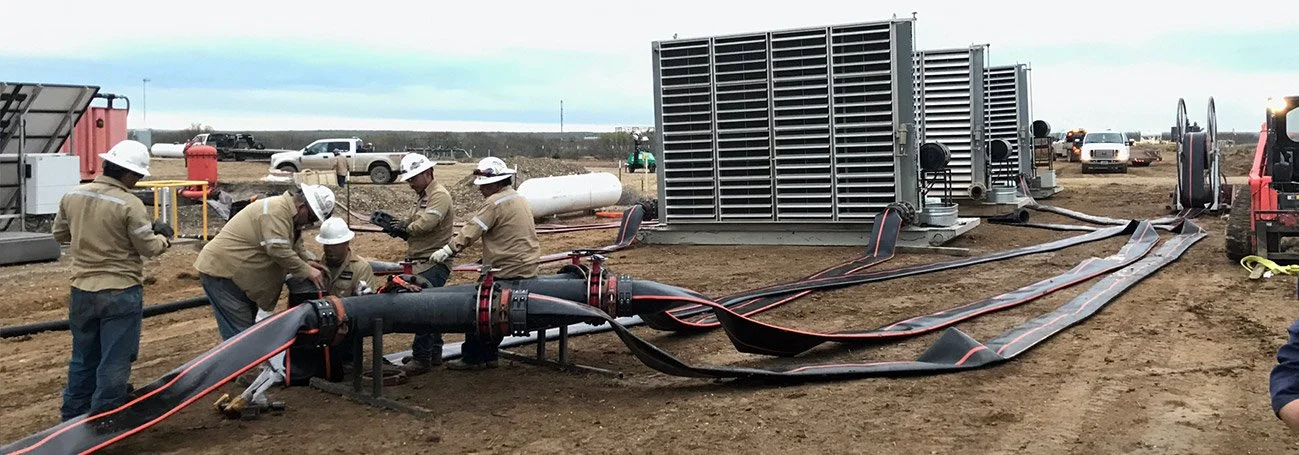 Qwik Pipe crew connecting a tank manifold to 10-inch lay flat hose at a frac water transfer site
