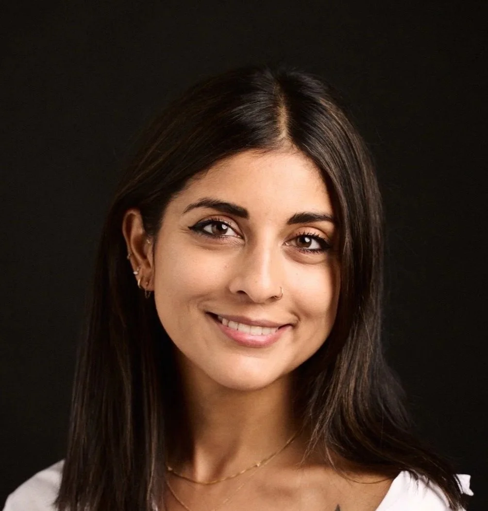 A young woman with dark brown hair, light skin, and a friendly smile against a black background.