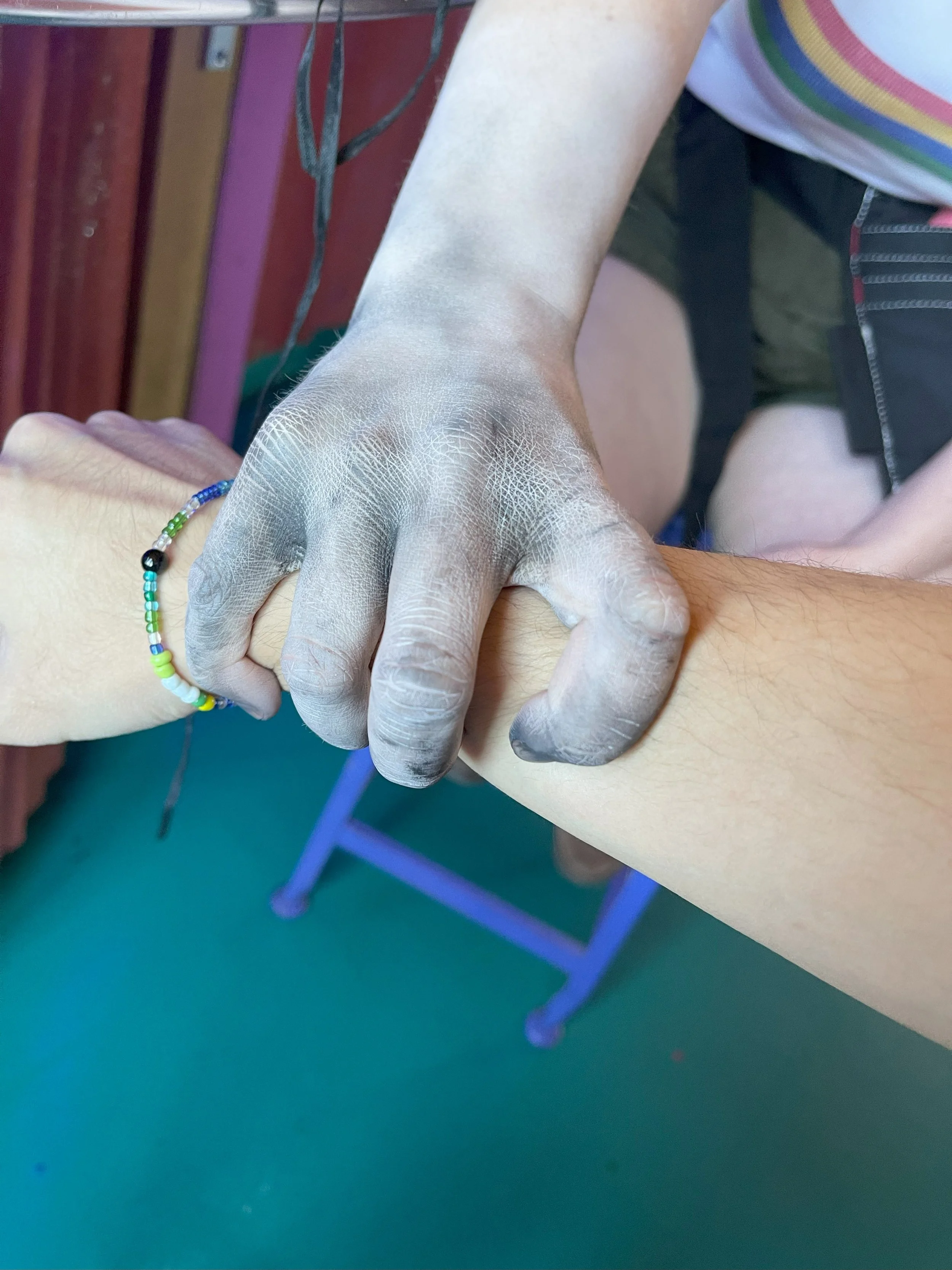 Close-up of a person's arm during a blood donation, with a medical technician's gloved hand holding the arm steady.