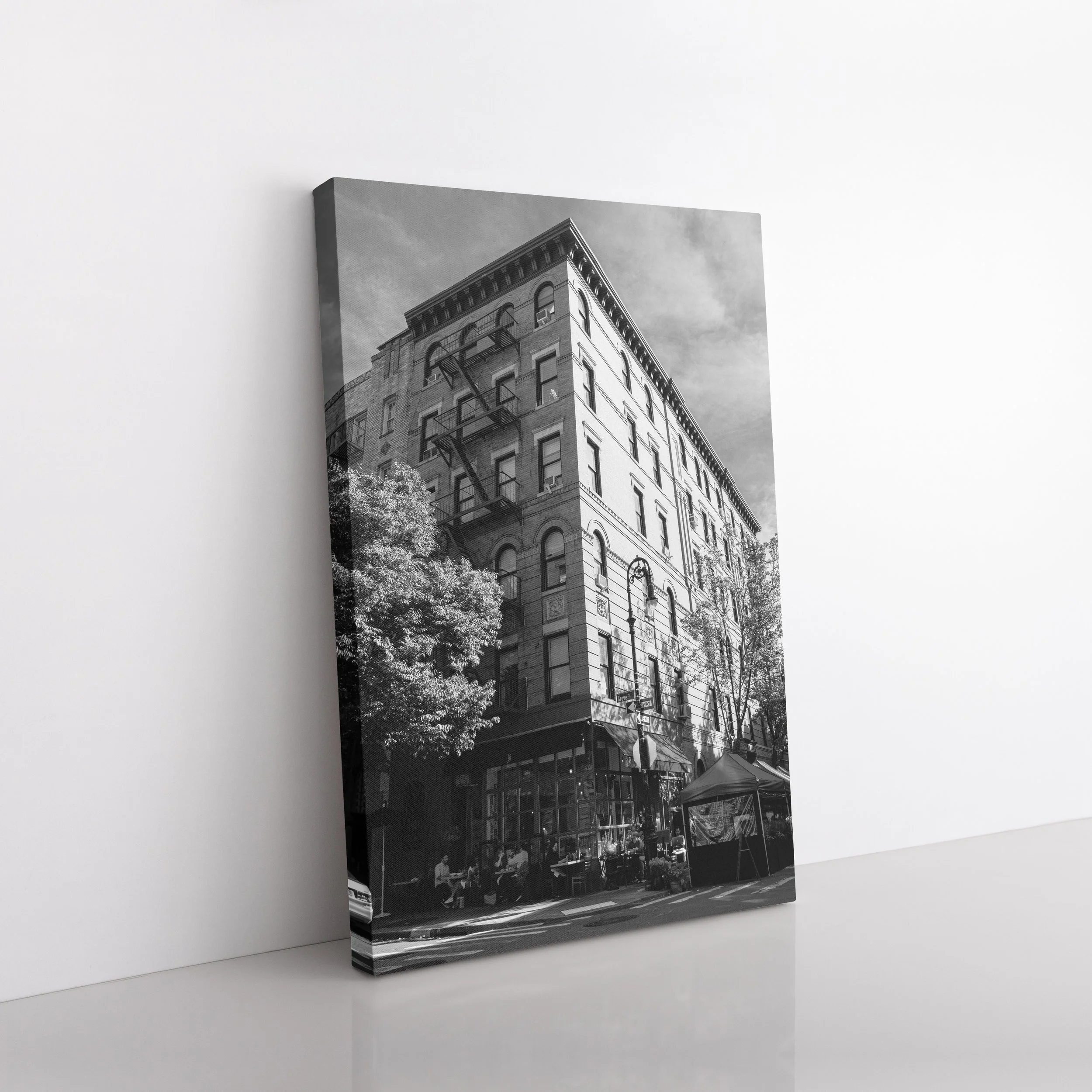 Angled side view of a Bedford and Grove black and white gallery-wrapped canvas resting on a white floor against a white wall.