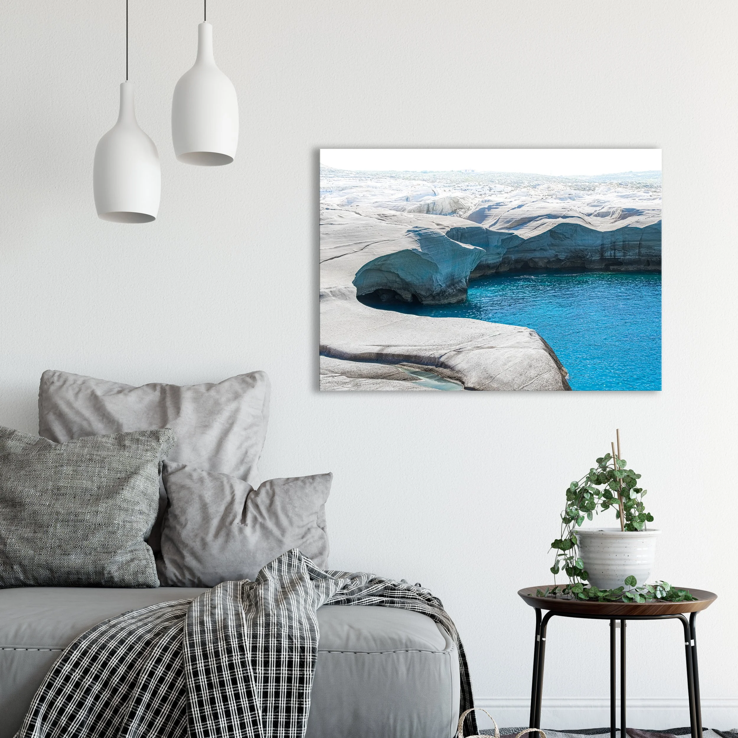 Fine art photography print of the striking white volcanic rock formations at Sarakiniko Beach in Milos, hanging above a gray sofa in a modern living room.