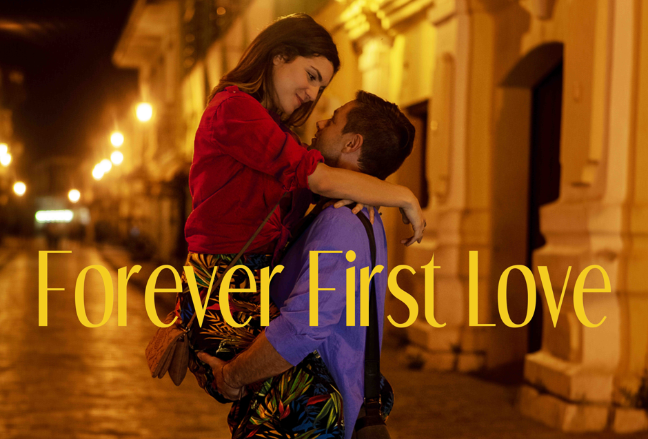A man carrying a woman in his arms on a city street at night, both smiling and looking at each other affectionately, with the text 'Forever First Love' overlaid.