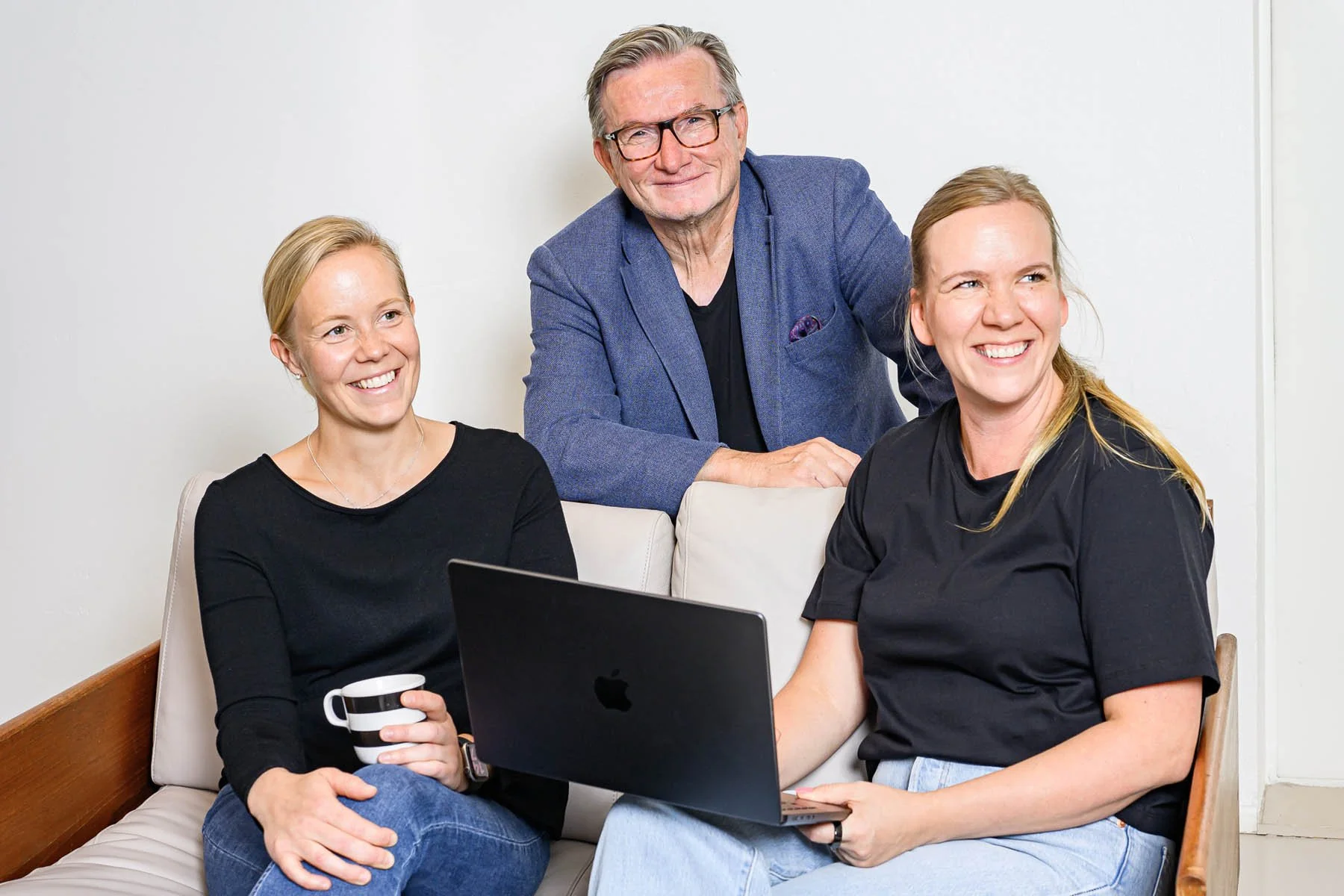 Helsinki Sales Academyn henkilöt istuvat yhdessä huoneessa, nauravat ja katsovat kameraan.
