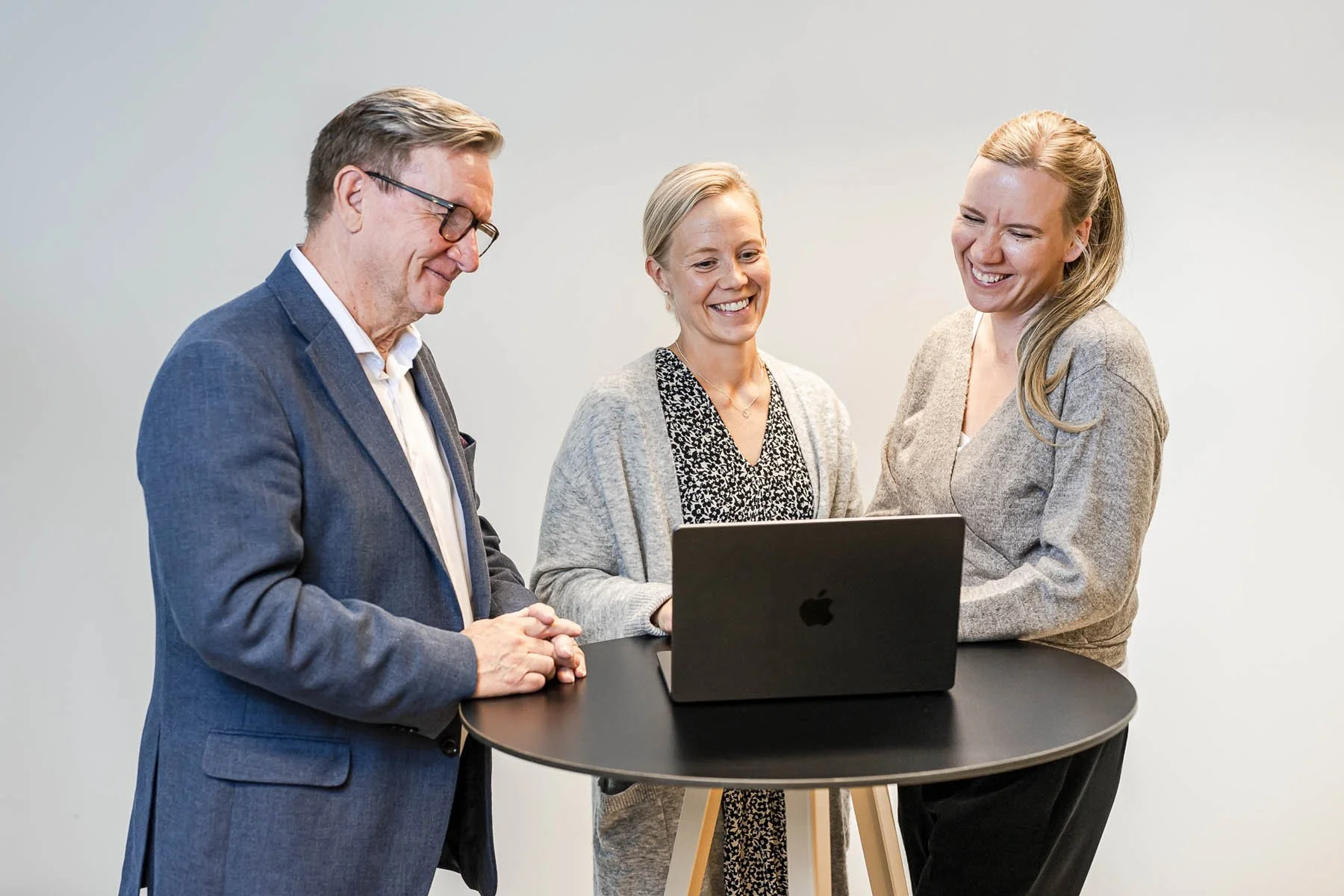 Helsinki Sales Academyn henkilöt katsovat ja hymyilevät tietokoneen näytölle, ja seisovat pöydän ympärillä.