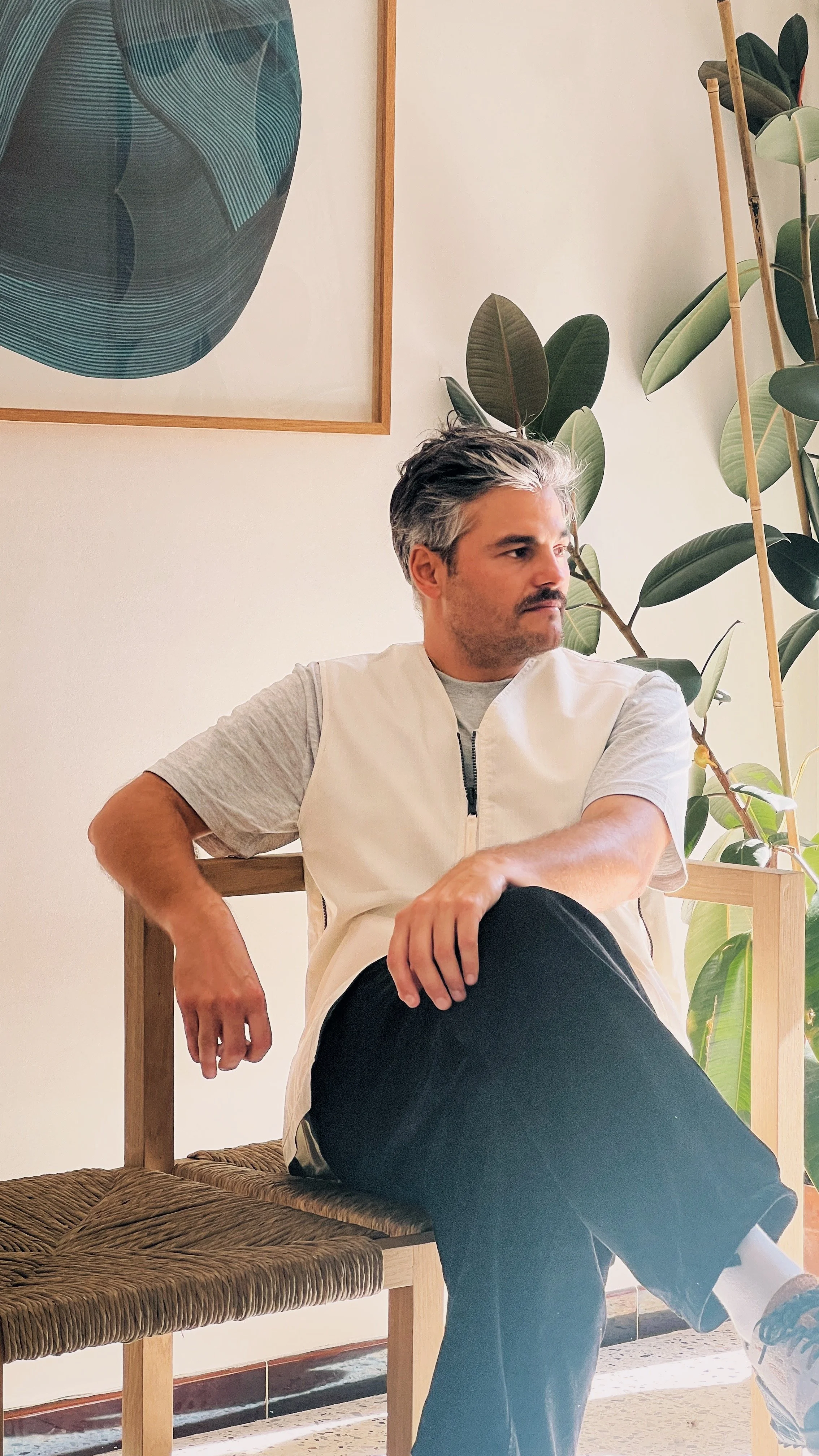 Alexandre Reignier assis sur un siège design en chêne massif et paillage naturel dans un intérieur minimaliste