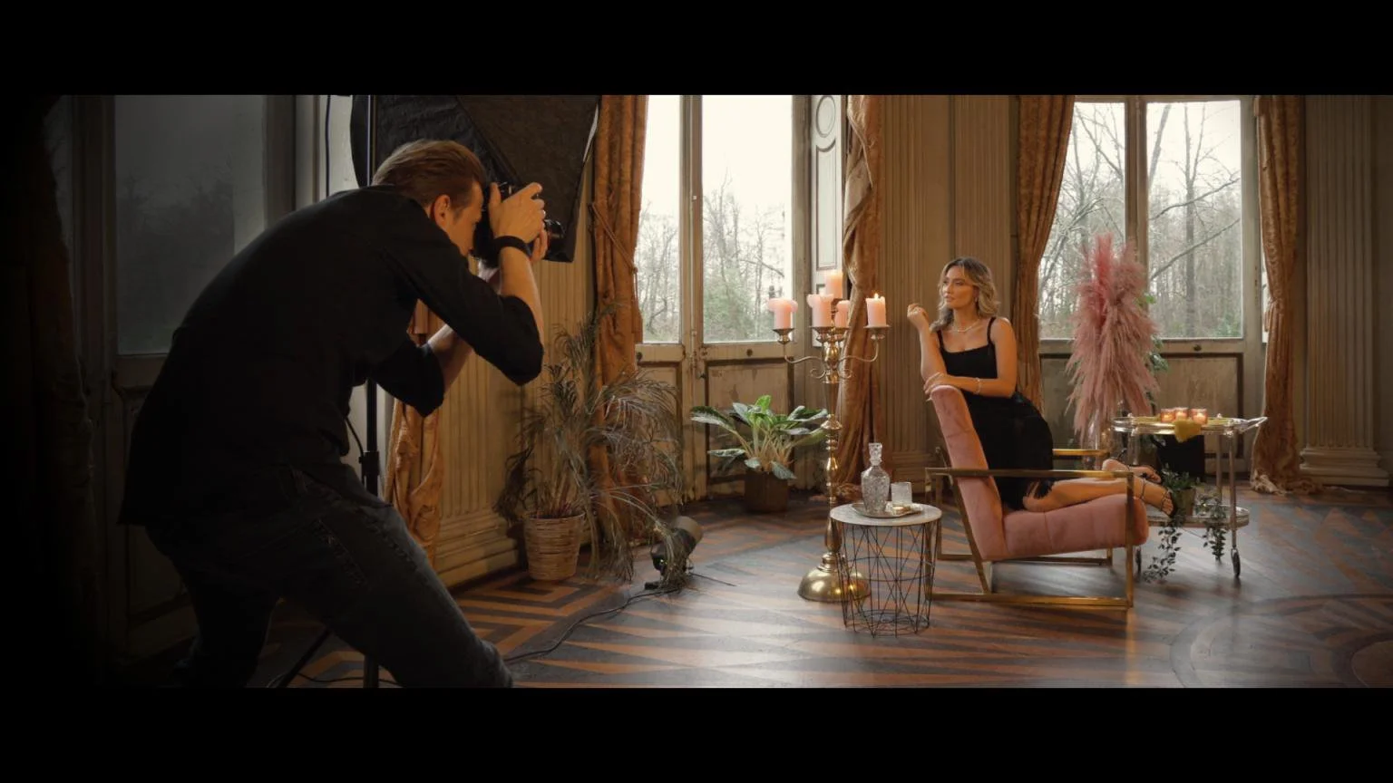 Lennart Knab photographing a woman in a black dress during an on-location boudoir session in a vintage salon with candles
