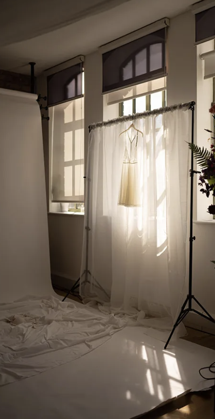 Boudoir Antwerp photography studio with natural light, white sheets, and lighting equipment