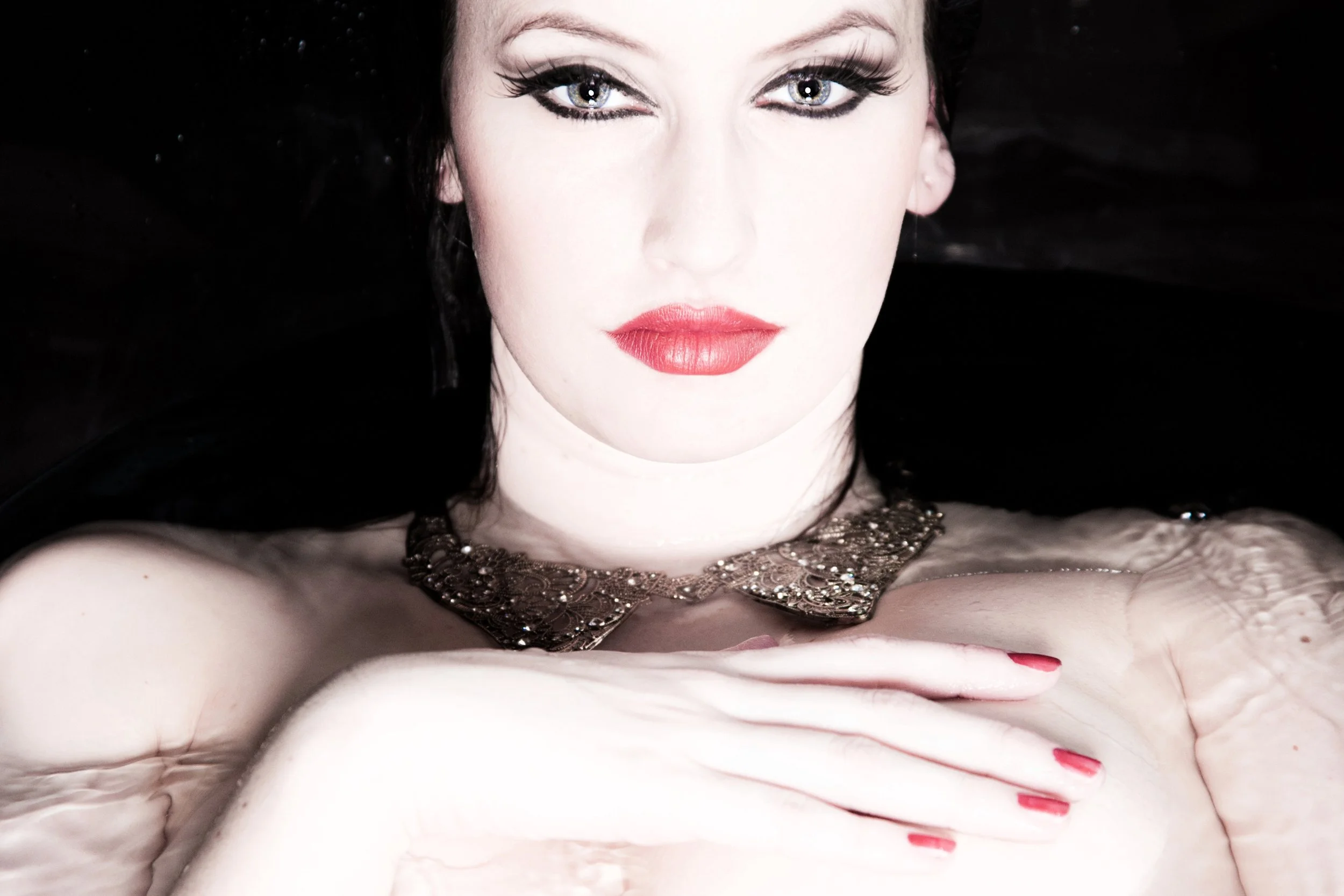 Artistic boudoir portrait with red lips and a jewelled collar, photographed in water against the shower wall