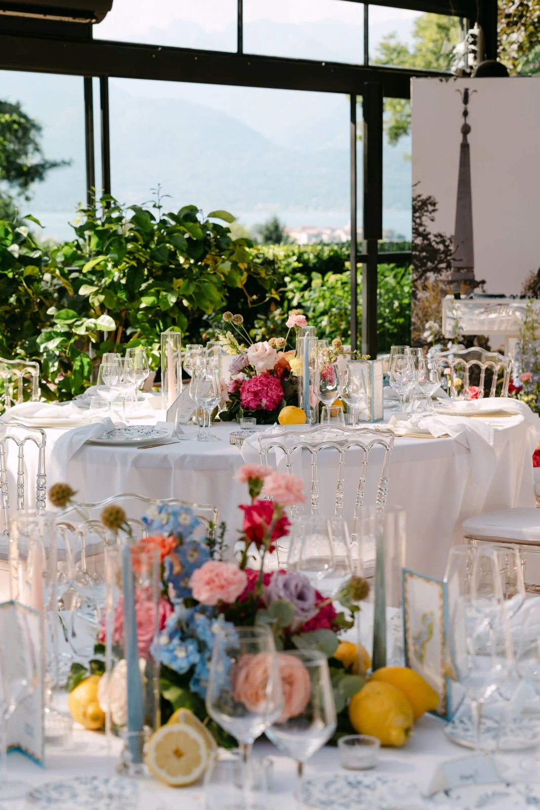 Elegant gedeckter Festtisch mit Blumenarrangements, Wein- und Wassergläsern, auf einer Terrasse mit Blick auf die Natur.