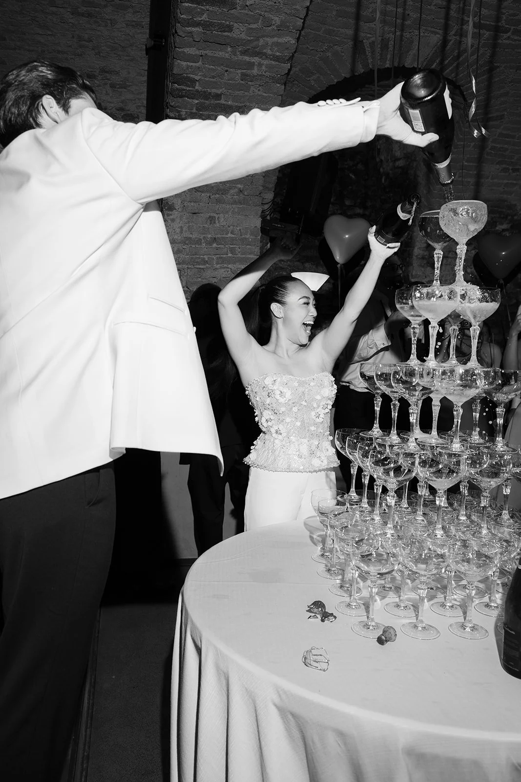 Ein glückliches Paar beim Feiern einer Hochzeit, das einen Champagner-Feuerwork auf einem Turm aus Sektgläsern genießt.