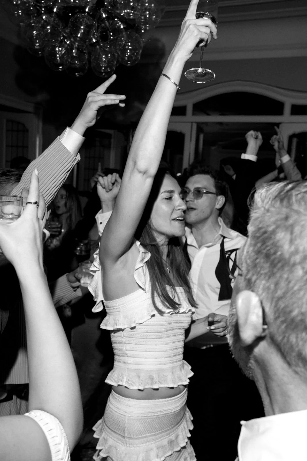 Menschen feiern und tanzen auf einer Party, einige halten Gläser mit Getränken hoch.