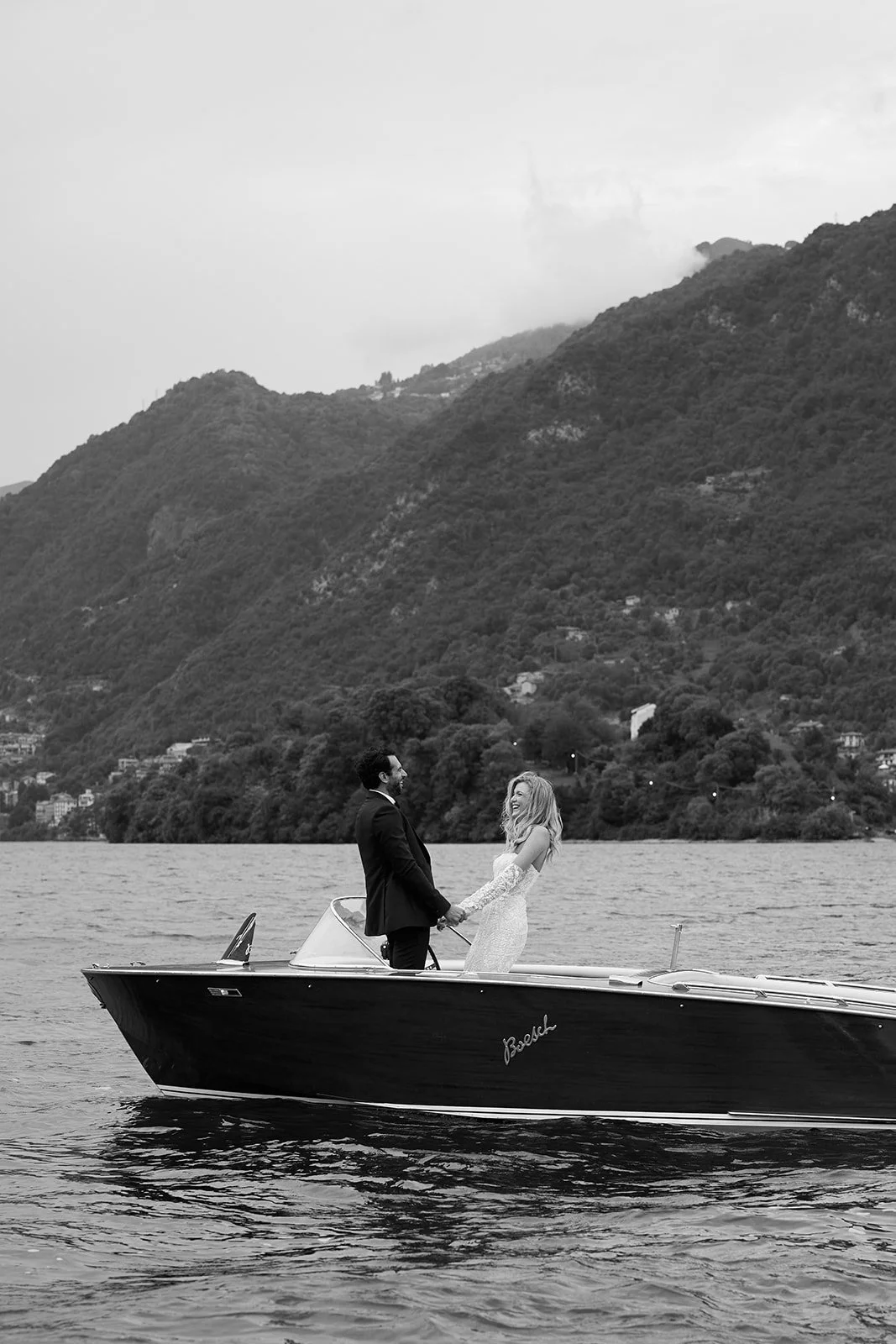 Paar auf einem Boot auf einem See, umgeben von Bergen, in schwarz-weiß.