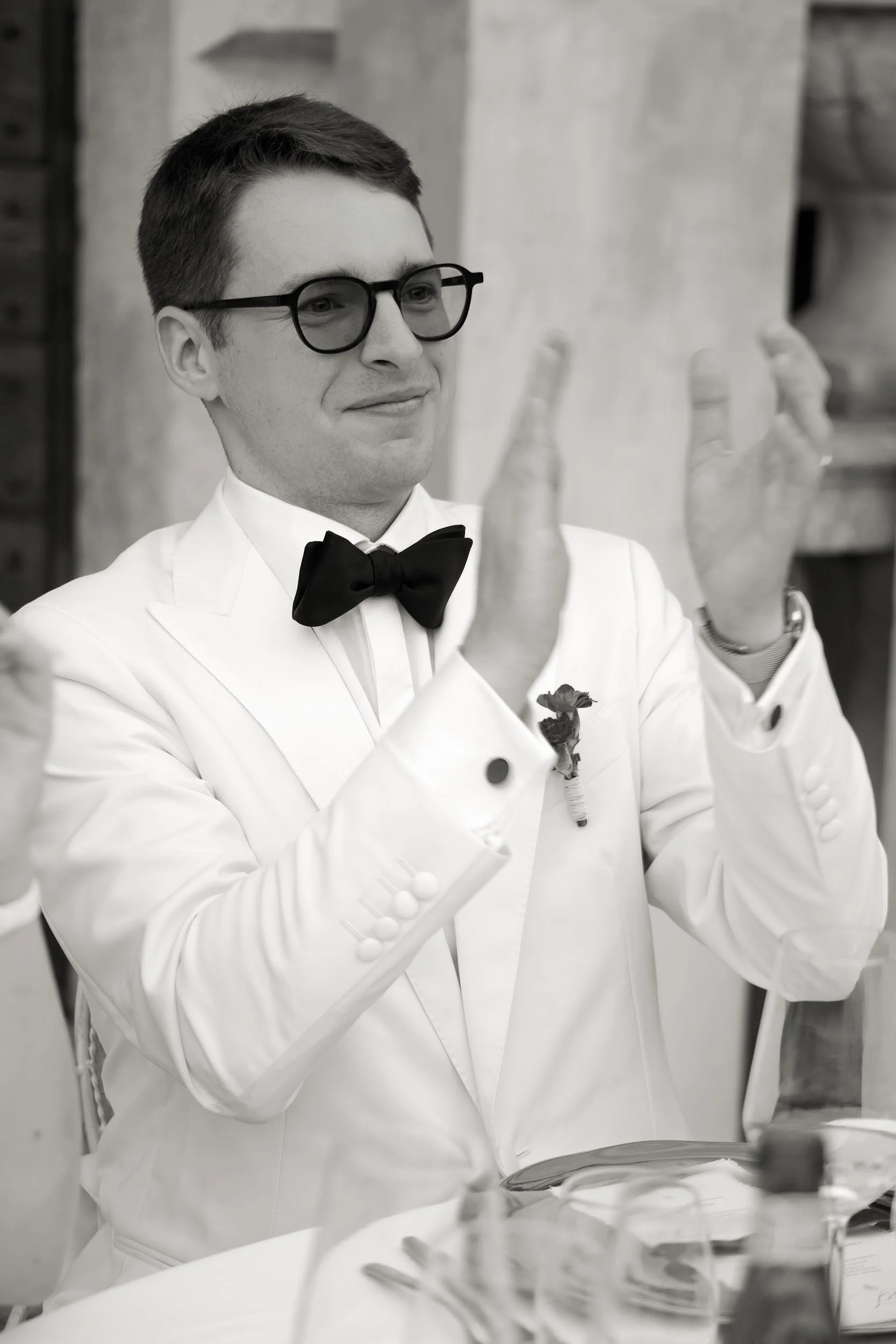 Ein Mann in formeller Kleidung mit Brille, der in einer Küchenumgebung steht.