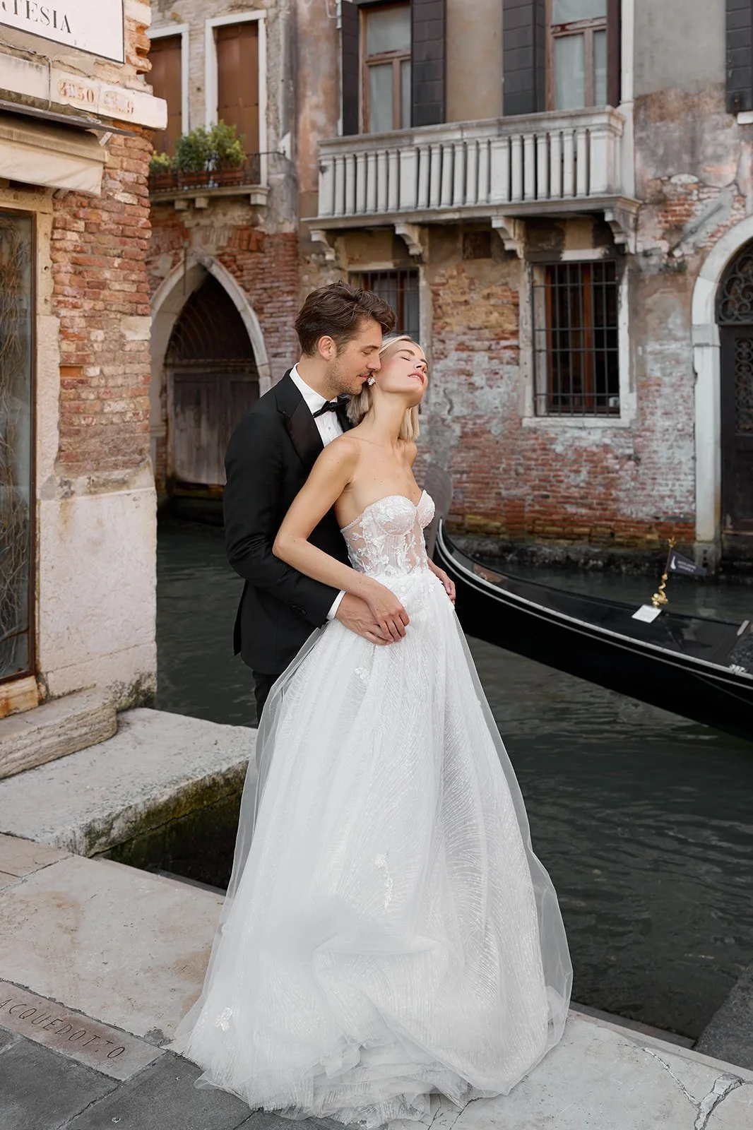 Ein Brautpaar in Hochzeitskleidung steht an einem Kanal in Venedig, Italien.