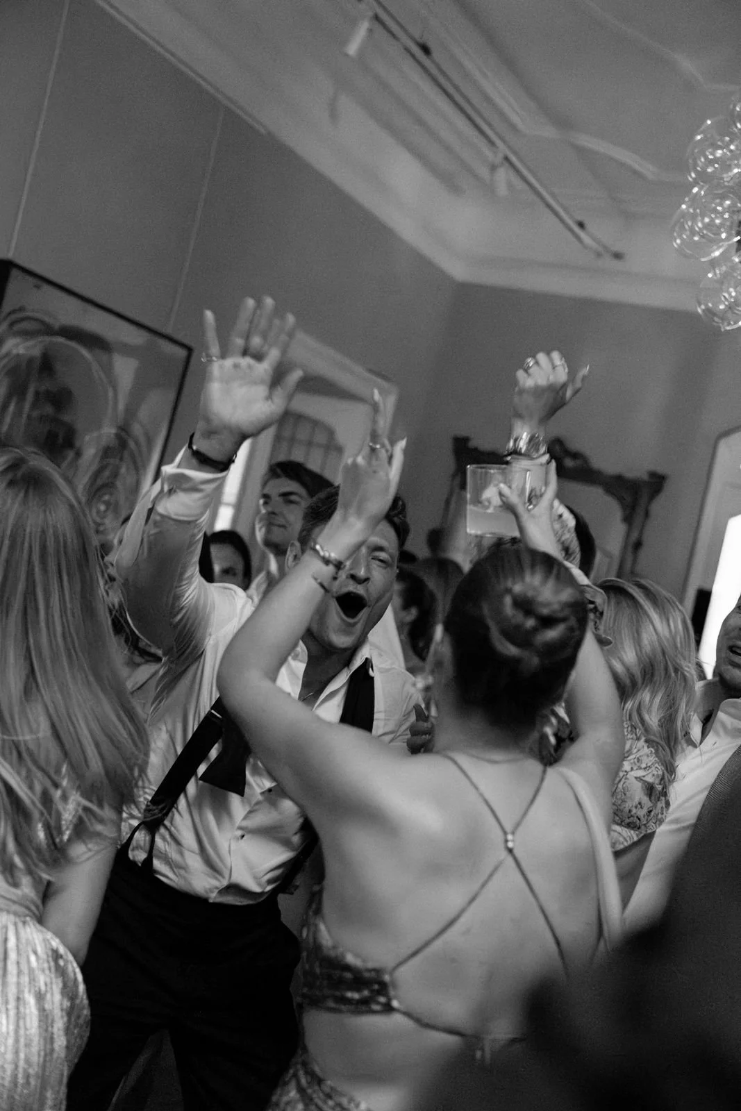 Menschen feiern auf einerParty, einige mit erhobenen Händen, lachen und haben Spaß.