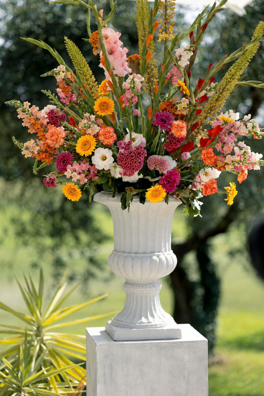 Bunter Blumenstrauß in einer weißen Vase im Freien mit grünem Hintergrund.